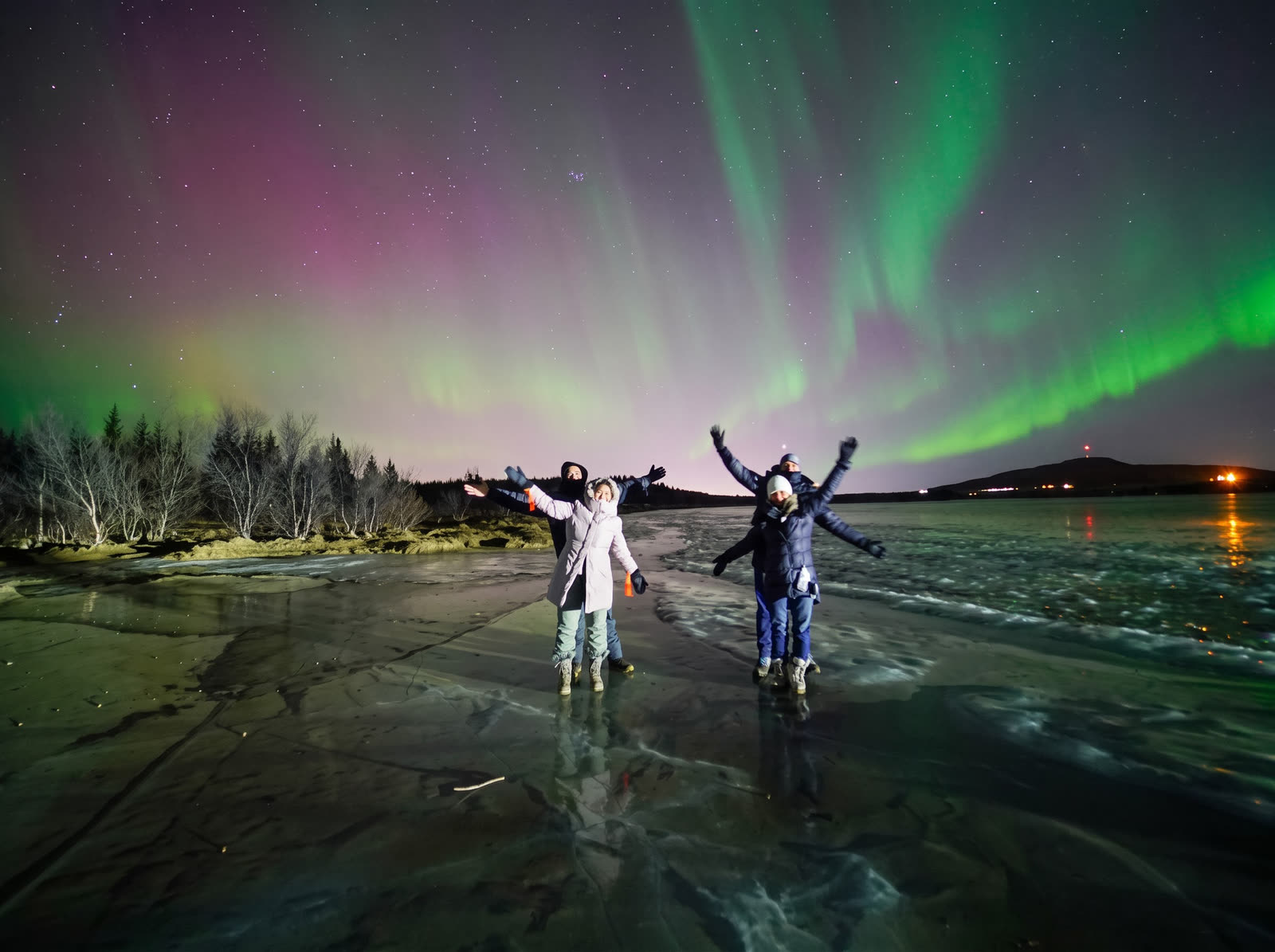 Nhóm du khách dang tay trên mặt hồ băng dưới cực quang, Iceland